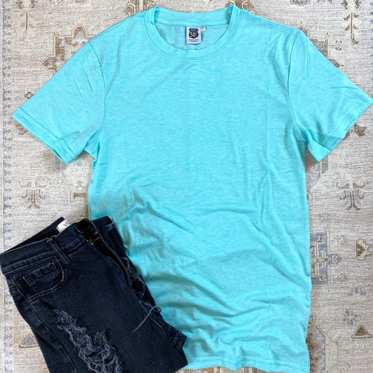 Aqua blue t-shirt laying flat on a rug background with a pair of black jeans